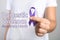 Woman holding purple ribbon on background, closeup. Symbol of Domestic Violence Awareness
