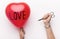 Woman holding red heart balloon with love text and pinned with scissors