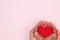 Woman holding red heart in hand on pink background with copy spa