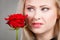 Woman holding red rose near face looking melancholic