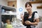 A woman holding a round bill in front of the dishwasher