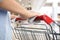 Woman holding shopping cart handle with tissue paper at supermarket. Preventive measure in public places during