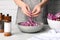 Woman holding shredded fresh red cabbage at grey marble table, closeup
