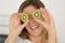 woman holding sliced kiwi against eyes