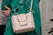 Woman is holding a small stylish bag clutch of soft beige colo