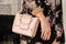 Woman is holding a small stylish bag clutch of soft beige colo