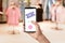 Woman holding smartphone with activated promo code in clothes store, closeup