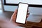 Woman holding smartphone mockup of blank screen and computer on the table office. Take your screen to put on advertising.