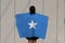 Woman holding Somalia flag on her shoulder and turn back on grey background