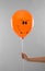 Woman holding spooky balloon for Halloween party on light grey, closeup