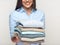 Woman holding stack of folded clothes.