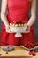 Woman holding summer sponge cake with fruits on ceramic cake sta