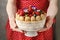 Woman holding summer sponge cake with fruits on ceramic cake stand