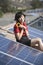 Woman Holding Sunflower By Solar Panel On Rooftop