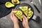 Woman holding tasty avocado toast over grey table