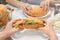 Woman holding tasty croissant sandwich over plate