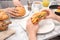 Woman holding tasty croissant sandwich over plate