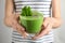 Woman holding tasty kale smoothie with chia seeds on light background, closeup