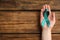 Woman holding teal awareness ribbon on wooden background, top view. Symbol of social and medical issues