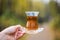 Woman holding traditional turkish cup with hot tea against unfocused forest