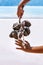 Woman holding tropical branch with necklace made of seashells at sea shore background close up