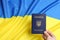 Woman holding Ukrainian internal passport on national flag, closeup.