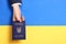 Woman holding Ukrainian internal passport over national flag, top view.