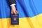 Woman holding Ukrainian internal passport over national flag, top view