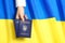 Woman holding Ukrainian internal passports over national flag, top view.