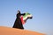 Woman holding the United Arab Emirates flag in the desert.
