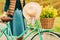 Woman holding vintage bicycle with hanging summer hat