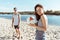 Woman holding volleyball ball in hands with man behind on beach