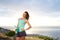 Woman holding water bottle in front of sunset by the sea