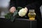 Woman holding white rose near black granite tombstone with candle outdoors, closeup. Funeral ceremony