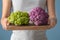 Woman holding wooden board with colorful cauliflowers, closeup