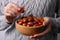 Woman holding wooden bowl with fresh Ziziphus jujuba fruits on light background, closeup