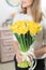 Woman holding yellow narcissus. Beautiful bouquet of spring daffodils in her hands as a gift.