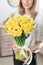 Woman holding yellow narcissus. Beautiful bouquet of spring daffodils in her hands as a gift.