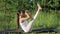 Woman holds balance on gymnastic rug. Outdoor yoga classes