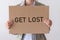 A woman holds a banner with the inscription GET LOST