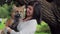 Woman holds black fox on hands, participates in photography in nature