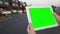 A woman holds a blank tablet PC with a green screen for your own custom content.