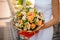 Woman holds a bouquet of kraspedia, roses, pion-shaped roses and succulents