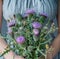 a woman holds a bouquet of thistles