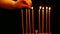 A woman holds a burning candle in her hand with which she lights candles in a candlestick for the Hanukkah. a woman lights candles