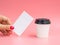 Woman holds empty business card near a small paper coffee cup on a pink background. White espresso cup with blank