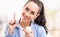 Woman holds face cream taken from a white packaging on her finger, smiling, cream also applied on her face