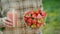 A woman holds a glass of tubers and a bowl of strawberry berries