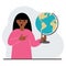 A woman holds a globe in his hand and points his finger at it. The concept of education, teacher, world conquest