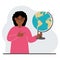 A woman holds a globe in his hand and points his finger at it. The concept of education, teacher, world conquest